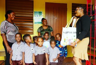 Educator, Jillian Wray-Robinson (right), addresses students and teachers at the Kitson Town Basic School in St. Catherine, on September 25, prior to handing over 15 time clocks to her former school. Others pictured are Principal, Charline Nathon (left), and teacher at the school, Precious White Thomas.