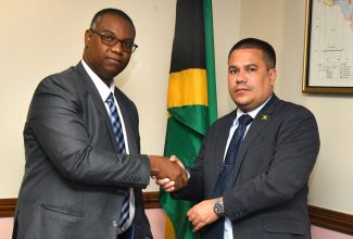 Minister without Portfolio in the Ministry of Economic Growth and Job Creation, Senator the Hon. Matthew Samuda (right), accepts a gift from Ambassador-designate to the Swiss Conferation, Dr. Richard Brown, when he visited the Ministry’s offices in St. Andrew on Thursday (August 31).