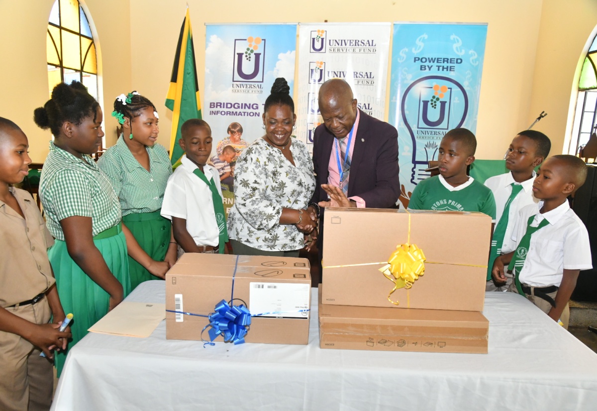 Chief Executive Officer of the Universal Service Fund (USF), Dr. Daniel Dawes (fourth right), hands over two desktop computers to Acting Principal of Bartons Primary School, Georgette Williams (centre). Sharing the moment are students of the institution. The handover ceremony was held on September 7 at the school’s location in Bartons District, St. Catherine. The contribution will enable the students to access digital learning resources, enhance their research capabilities, and develop essential computer literacy skills.