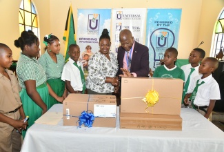 Chief Executive Officer of the Universal Service Fund (USF), Dr. Daniel Dawes (fourth right), hands over two desktop computers to Acting Principal of Bartons Primary School, Georgette Williams (centre). Sharing the moment are students of the institution. The handover ceremony was held on September 7 at the school’s location in Bartons District, St. Catherine. The contribution will enable the students to access digital learning resources, enhance their research capabilities, and develop essential computer literacy skills.