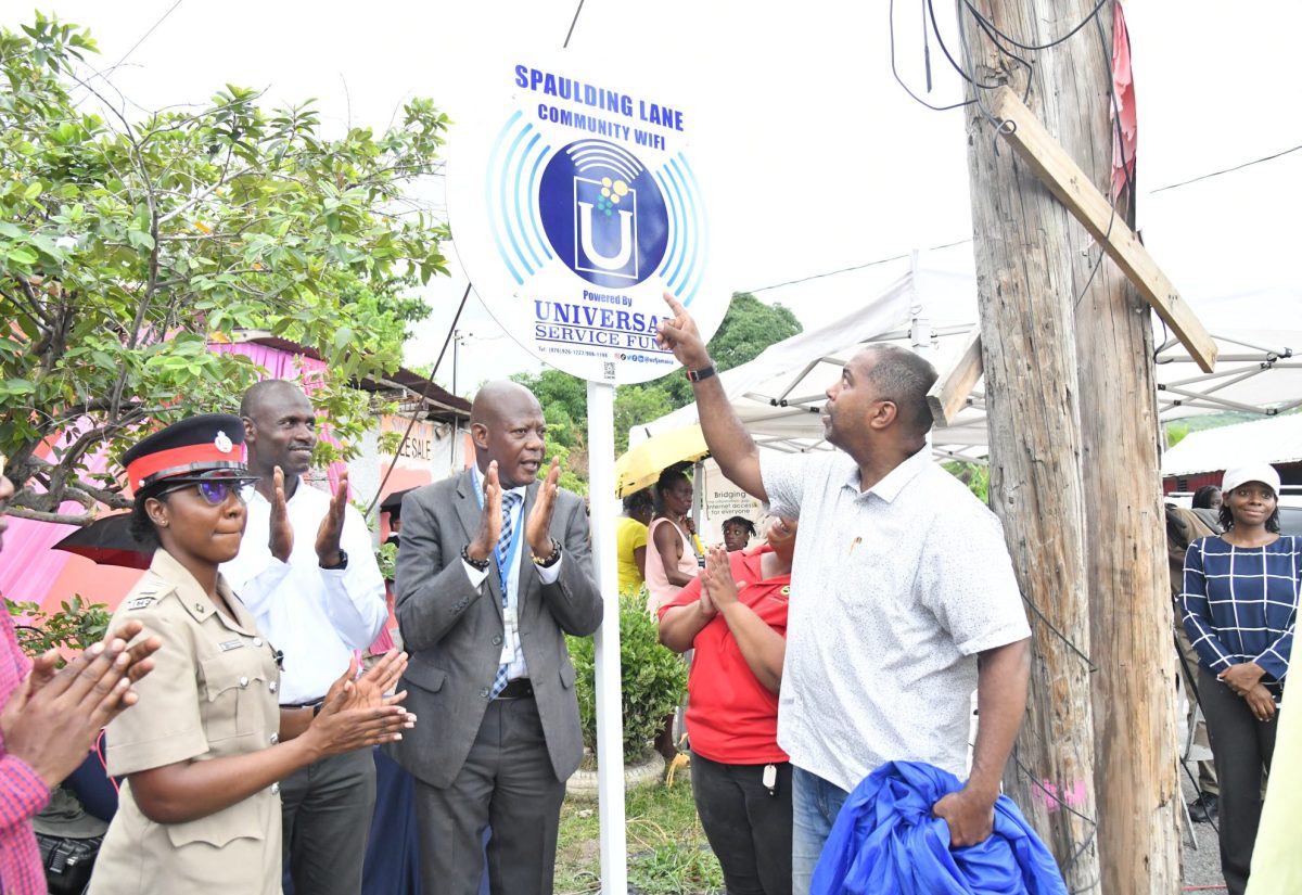 Chief Executive Officer, Universal Service Fund (USF), Daniel Dawes (second right), applauds as Member of Parliament, St. Andrew South Eastern, Julian Robinson (right), points to the newly unveiled sign to signal the launch of community Wi-Fi service at Spaulding Lane in Swallowfield, St. Andrew, on September 11. Sharing in the occasion (from second left) are Inspector Shantae Coddington of the Jamaica Constabulary Force (JCF) and Pastor, Church of God of Prophesy, Rev. Timon Waugh. The launch of the Community Wi-Fi initiative at Spaulding Lane signifies a strategic effort to bring digital inclusion to the heart of the community.
