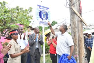 Chief Executive Officer, Universal Service Fund (USF), Daniel Dawes (second right), applauds as Member of Parliament, St. Andrew South Eastern, Julian Robinson (right), points to the newly unveiled sign to signal the launch of community Wi-Fi service at Spaulding Lane in Swallowfield, St. Andrew, on September 11. Sharing in the occasion (from second left) are Inspector Shantae Coddington of the Jamaica Constabulary Force (JCF) and Pastor, Church of God of Prophesy, Rev. Timon Waugh. The launch of the Community Wi-Fi initiative at Spaulding Lane signifies a strategic effort to bring digital inclusion to the heart of the community.