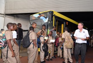 Minister of Science, Energy, Telecommunications and Transport, Hon. Daryl Vaz (right), observes students entering buses operated by the Jamaica Urban Transit Company (JUTC) at the Half-Way Tree Transport Centre in St. Andrew, today (September 11).