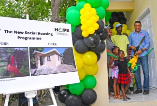 Prime Minister, the Most Hon. Andrew Holness (right), cuts the ribbon to hand over a new three-bedroom house to Leroy Grant (second right) and his family in Buff Bay, Portland on September 8. Looking on (from left) are Mr. Grant’s spouse, Latoya Bryan; and Member of Parliament for Portland Western, Hon. Daryl Vaz (partially hidden). Mr. Grant’s daughter and niece (in front), also share the moment.