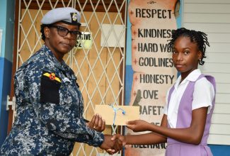Jamaica Defence Force (JDF) Warrant Officer and member of the Red Hills Primary School Past Students’ Association, Angi Lisa Chambers (left), makes a presentation to Christeanna Walters. Occasion was a ceremony at the institution on September 26 to hand over grants totalling $100,000 to 10 former students who performed well in the recent Primary Exit Profile (PEP) examinations.