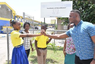 Top girl in the Primary Exit Profile at the St. Catherine-based Old Harbour Primary School, Jourdyne Anderson (left) is congratulated by Principal of the institution, George Goode (right). Looking on are Althea Smith (left), mother of top boy Daniel McLaren (centre), and Grade-six teacher at the school, Natalie Mitchell Warren.