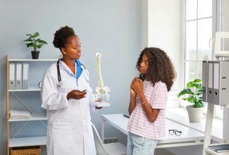 Female doctor tells preteen girl about spinal scoliosis 