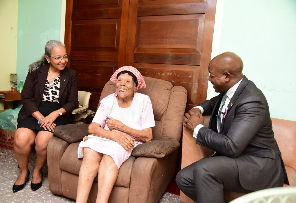 Minister of Labour and Social Security, Hon. Pearnel Charles Jr. and Permanent Secretary in the Ministry, Colette Roberts Risden (left), share a light moment with 101-year-old Francis Knight while visiting her home in Kingston on October 3. The visit, which included the presentation of a gift basket, was part of activities for Senior Citizens’ Month.

 