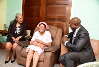 Minister of Labour and Social Security, Hon. Pearnel Charles Jr. and Permanent Secretary in the Ministry, Colette Roberts Risden (left), share a light moment with 101-year-old Francis Knight while visiting her home in Kingston on October 3. The visit, which included the presentation of a gift basket, was part of activities for Senior Citizens’ Month.