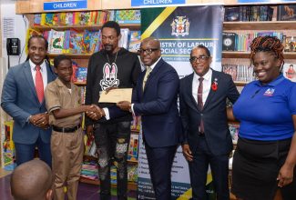 Minister of Labour and Social Security, Hon. Pearnel Charles Jr. (third right), presents a gift certificate to Bobby Carson Jr. (second left) during a presentation ceremony held for residents of Gregory Park, St. Catherine, who were affected by a firebombing incident earlier this year. The ceremony was held at the Kingston Bookshop, Portmore Town Centre, St. Catherine, on Thursday (October 5). Others (from left) are State Minister in the Ministry of Foreign Affairs and Foreign Trade and Member of Parliament for St. Catherine East Central, Hon. Alando Terrelonge; Bobby Carson Sr.; State Minister in the Ministry of Labour and Social Security, Dr. the Hon. Norman Dunn, and Supervisor, Kingston Bookshop, Portmore, Karaoke Harrison. The gift certificates, valued $15,000.00 each, are redeemable at Kingston Bookshop branches islandwide.