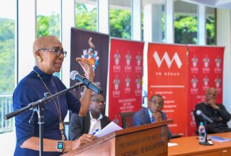 Minister of Education and Youth, Hon. Fayval Williams (at podium), addresses the University of the West Indies (UWI) Colloquium on Financing Tertiary Education, held at UWI’s Regional Headquarters in Kingston on Wednesday (October 11). Looking on (seated from left) are UWI Mona Principal, Professor Densil Williams; President and Chief Executive Officer (CEO) of VM Group, Courtney Campbell; and UWI Vice Chancellor, Professor Sir Hilary Beckles.