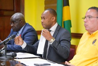 Managing Director of the Transport Authority, Ralston Smith (centre), displays the list of prescribed fares for public passenger vehicles, which are to take effect on Sunday, October 15, at a Transport Stakeholder Press Conference, at the Ministry of Science, Energy, Telecommunications and Transport. on Thursday (October 12). Also participating in the press conference are Minister of Science, Energy, Telecommunications and Transport, Hon. Daryl Vaz (right) and Director General of the Island Traffic Authority, Colonel Daniel Pryce.

