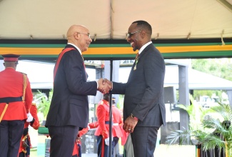 Governor-General, His Excellency the most Hon. Sir Patrick Allen (left), congratulates Immediate Past President of the Jamaica Civil Service Association (JCSA), O’Neil Grant, after presenting him with the insignia for the Order of Distinction (Officer Class), at the National Honours and Awards ceremony at King’s House on National Heroes Day, October 16.
