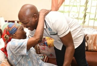 Minister of Labour and Social Security, Hon. Pearnel Charles Jr. (right), is warmly embraced by 105-year-old Julina McDonald, during a visit to her home in May Pen, Clarendon on Friday (Oct. 20). Minister Charles Jr. paid a special visit to the centenarian and presented her with a gift basket.