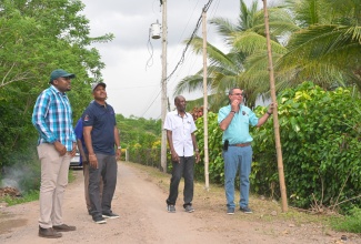 Minister of Science, Energy, Telecommunications and Transport, Hon. Daryl Vaz (right), holds a makeshift light pole while on a tour of the Citron Street community in Clarendon North Central on October 5. The area is slated for electricity upgrade under the Rural Electrification Programme (REP), administered by the Jamaica Social Investment Fund (JSIF). Others pictured (from left) are Member of Parliament for Clarendon North Central, Hon. Robert Morgan; Managing Director of JSIF, Omar Sweeney, and Minister of State in the Ministry of Science, Energy, Telecommunications and Transport, Hon. J.C. Hutchinson.
