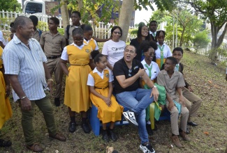 Minister of Health and Wellness, Dr. the Hon. Christopher Tufton (seated, second left), sits on a wellness bench with students of the B.B. Coke High School in St. Elizabeth. The bench was unveiled during a mental wellness session held at the school on Thursday (October 26) in collaboration with the Ministry of Education and Youth. Joining the Minister are Chairman of the school board, Cetany Holness (left); Acting Principal of B.B. Coke High, Liteasha Gallimore (standing, third right); and Director of Child and Adolescent Mental Health in the Ministry of Health and Wellness, Dr. Judith Leiba (standing, fourth right).