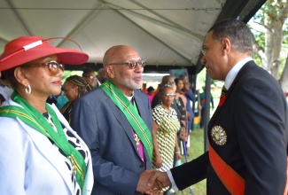 Prime Minister, the Most Hon. Andrew Holness (right), greets recipient of the Order of Jamaica (OJ), Anglican Archbishop of the West Indies, His Grace, the Most Reverend Howard Gregory (second left), during the Ceremony of Investiture and Presentation of National Honours and Awards, held on the lawns of King’s House on Monday (October 16). Sharing in the moment is fellow OJ recipient and reggae songbird, Marcia Griffiths (left). 