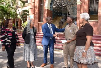 Minister of Labour and Social Security, Hon. Pearnel Charles Jr. (centre), shakes hands with St. George’s College student Demetri Callum, during the presentation of a cheque to the youngster on Monday (October 2) at the school. The presentation came in response to a request for assistance in covering the cost of Mr. Callum’s studies. Sharing the moment are (from left) Chief Technical Director in the Labour Ministry, Audrey Deer Williams; Permanent Secretary, Colette Roberts Risden; and St. George’s College Principal, Margaret Campbell. 