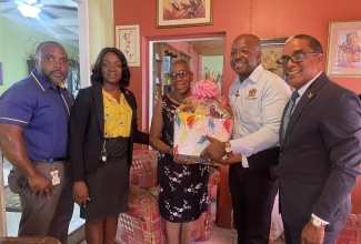 Minister of Labour and Social Security, Hon. Pearnel Charles Jr. (second right), presents a gift basket to Barbara Forbes (centre) during a visit to her home in Hughenden, St. Andrew on Wednesday (October 4). Sharing the moment (from left) are National Council for Senior Citizens (NCSC) Social Worker and Parish Officer for St. Andrew, Marlon Johnson; Executive Director of the NCSC,  Cassandara Morrison;  and State Minister in the Ministry, Hon. Dr. Norman Dunn. A team from the Ministry visited with several senior citizens in the Corporate Area on Wednesday and presented them with gift baskets as part of Senior Citizens’ Month celebrations.