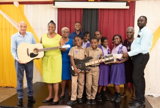Chairman of the Board at the Barrett Town Primary School in St. James, Bertram Wright (left), receives a donation of musical instruments from Dr. Doreen Miller Diagne (second left), daughter of late Barrett Town community stalwarts, Dudley and Iris Miller. The handover ceremony was held in the community recently. Sharing the moment are daughter, Sandra Miller Hall (third left); Deputy Mayor of Montego Bay, Councillor Richard Vernon (fourth left); daughter, Sheila Forte-Trammell (second right); Councillor for the Rose Hall Division, Anthony Murray (right), and students of Barrett Town Primary School.

