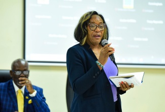 Director of Standards, Bureau of Standards Jamaica, Julia Bonner Douett, speaks during a meeting of the National Disaster Risk Management Council on Tuesday (October 31), at the Ministry of Local Government and Community Development, on Hagley Park Road in Kingston. Listening is Minister of Local Government and Community Development, Hon. Desmond McKenzie.
