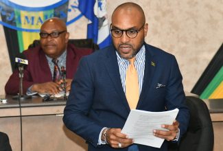 Chief Executive Officer, Kingston and St. Andrew Municipal Corporation (KSAMC), Robert Hill (foreground) addressing Tuesday’s (November 14) sitting of the KSAMC. The meeting was held at the Corporation’s offices on Church Street, downtown Kingston. Listening is Deputy Mayor of Kingston, Councillor Winston Ennis.