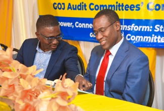 Minister of Finance and the Public Service, Dr. the Hon. Nigel Clarke (right), and PWC Jamaica Territory Leader/Senior Partner, Bruce Scott, peruse a book during Thursday’s (November 9) Government of Jamaica Audit Committees’ Conference 2023 at The Summit in Kingston.

