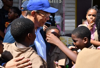 Minister of National Security, Hon. Dr. Horace Chang (centre), embraces students of the Chetwood Memorial Primary School in St. James on Tuesday (November 7), during a visit to the institution to offer support in the wake of a shooting incident on Monday (November 6) that claimed the lives of two male students of the school.

