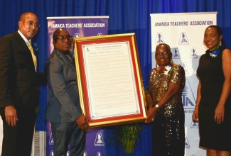 Minister of State in the Ministry of Education and Youth, Hon. Marsha Smith (right), shares in the presentation of a framed citation to the Jamaica Teachers’ Association (JTA) 2023 Roll of Honour Awardee,  Maudlyn Wright Shaw (second right), at the recent awards ceremony held at The Jamaica Pegasus hotel in New Kingston. Making the presentation is JTA President, Leighton Johnson (second left), while Attorney-at-law, Peter Champagnie, who was the guest speaker, also shares the moment.

