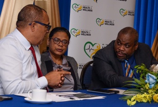 Minister of Health and Wellness, Dr. the Hon. Christopher Tufton (left), in dialogue with Chief Medical Officer, Dr. Jacquiline Bisasor-McKenzie and Chief Technical Director, Policy, Planning and Development at the Ministry of Health and Wellness, Howard Lynch, at the presentation of the Ministry