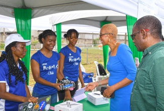 Minister of Education and Youth, Hon. Fayval Williams (second right), engages with Immaculate Conception High School Robotics Club team members (from left), Rheanna Robinson, Sage Thompson, and Gladenique Bennett. Looking on is President and Chief Executive Officer, EVPower Jamaica Limited, Wayne McKenzie. Occasion was the Secondary Schools’ Robotics Competition on November 29, at EVPower’s location at 1 Wikip Place, Marcus Garvey Drive, Kingston 11.