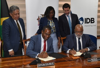 Minister of Finance and the Public Service, Dr. the Hon. Nigel Clarke (left, seated) and General Manager, Country Department Caribbean Group and Country Representative, Jamaica, Inter-American Development Bank (IDB), Anton Edmunds (right, seated) affix their signatures to the US$1.2-million technical cooperation agreement between the Government of Jamaica (GOJ) and IDB to strengthen the country’s public-private partnership (PPP) programme, during a ceremony at the Finance Ministry in Kingston on Thursday (November 9). Witnessing the proceedings (from left, standing) are Acting Managing Director, Development Bank of Jamaica, David Wan; Permanent Secretary, Ministry of Economic Growth and Job Creation, Arlene Williams; and Chief Operations Officer, IDB, Lorenzo Escondeur.

