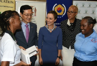 Minister of Foreign Affairs and Foreign Trade, Senator the Hon. Kamina Johnson Smith (centre), and Minister of Education and Youth, Hon. Fayval Williams (second right), engage in conversation with student at Meadowbrook High School, Jadiel Lindsay (left), during the handover of 4,103 tablets computers by the Republic of Korea, valued at over $92 million, at a ceremony held at the offices of the Ministry of Foreign Affairs and Foreign Trade in downtown Kingston, today (November 7). Others pictured (from left) are Korea’s Chargé d’Affaires, Jin-wook Kim, and student at the Abilities Foundation, Tanisha Gaynor.