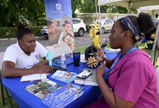 Customer Service Representative at the National Housing Trust (NHT), Betty-Ann Griffiths, interacts with an attendee at the recent Service Excellence Day function at the Jamaica House back lawns in St. Andrew.

 