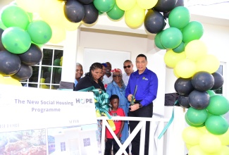 Prime Minister, the Most Hon. Andrew Holness (right), cuts the ribbon to mark the handover of a two-bedroom house, built under the New Social Housing Programme (NHSP), to Merlin Smart, (second right) in Greenvale, Manchester on Friday (December 15). Others (from left) are the beneficiary’s daughter, Charmaine Smart; great grandson, Uzair Brown; and Member of Parliament for Manchester North Western, Mikael Phillips.