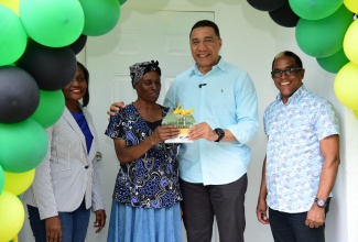 Prime Minister the Most. Hon. Andrew Holness (second right), gives the keys to beneficiary of a one-bedroom unit under the New Social Housing Programme (NSHP) in Belfield, St. Mary, Susettee Hudson, at the official handover of the house on December 21. Looking on (from left) are Permanent Secretary in the Ministry of Economic Growth and Job Creation, Arlene Williams and Member of Parliament for St. Mary, South Eastern, Dr. the Hon. Norman Dunn.