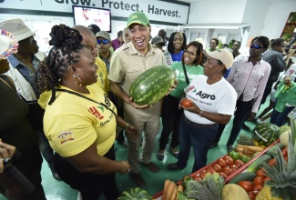 Prime Minister, the Most Hon. Andrew Holness (centre), is all smiles as he holds a large watermelon that was on display at the Denbigh Agricultural, Industrial and Food Show in May Pen, Clarendon, while interacting with patrons and exhibitors.