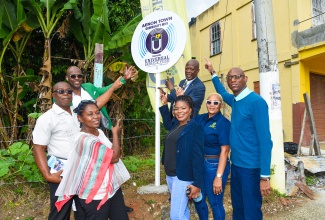 Chief Executive Officer, Universal Service Fund (USF), Dr. Daniel Dawes (fourth right), points to the Aenon Town community Wi-Fi sign, which was unveiled during Friday’s (December 8) launch of the service in the Clarendon community. Sharing in the moment (from left) are USF Director of Projects, Jaime Robinson; Social Development Commission (SDC) Community Development Officer, Nicola Bailey; Community Representative, Simone Cross; Member of Parliament for Clarendon Northern, Dwight Sibblies; Pastor of the United Emmanuel Church of God, Aenon Town, Albert Cooper; and Principal of Aenon Town Primary School, Margarette Lothian.