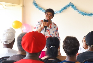 Clerk to the Houses of Parliament, Valrie Curtis, addresses the audience at the annual Elderly Treat and Health Fair on December 13 at Gordon House. Approximately 100 elderly persons who reside at Mark Lane and surrounding communities, downtown Kingston, received care packages containing food items and toiletries. The annual event returned this year after a hiatus due to the COVID-19 pandemic.