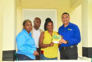 Prime Minister, the Most Hon. Andrew Holness (right), hands over the keys of a two-bedroom house, built under the New Social Housing Programme (NHSP), to Bridget Brown  (second right) in Morgan’s Forrest, Clarendon on Friday (December 15). Looking on (from left) are Chairperson for the Oversight Committee of the NSHP, Judith Robb Walters; and Member of Parliament for Clarendon Northern, Dwight Sibblies.