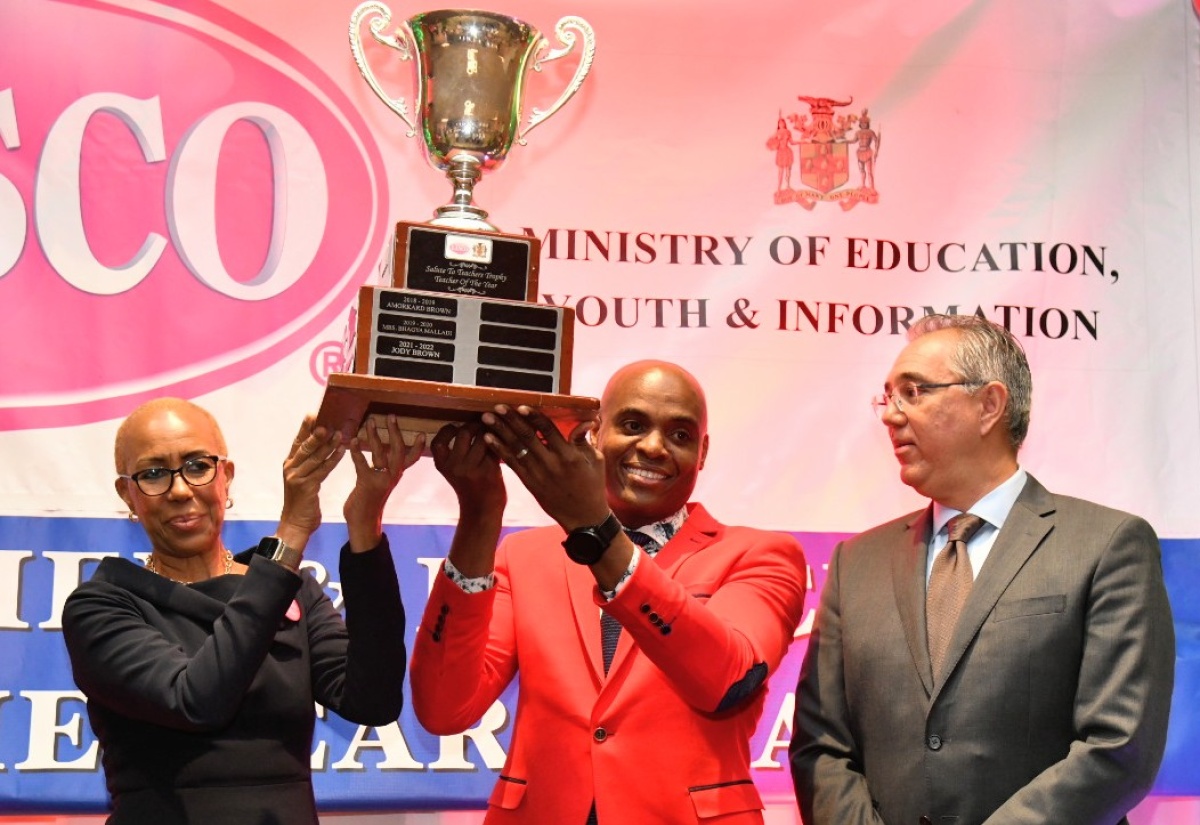 Minister of Education and Youth, Hon. Fayval Williams (left), presents the LASCO/Ministry of Education and Youth/Jamaica Teaching Council 2023 Teacher of the Year trophy to St. Andrew High School for Girls Chemistry teacher, Franklin Burrell (centre), during Tuesday