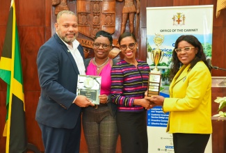 Cabinet Secretary, Audrey Sewell (right), presents the first-place trophy in the Office of the Cabinet’s Front Office Décor Competition to the team from the Ministry of Education and Youth, during the awards ceremony at Jamaica House on Thursday (December 21). Accepting the award (from left) are Customer Service Assistant, Dwayne Goodison; Monitoring and Evaluation Officer, Paula Lindsay; and Director of Customer Service, Anita Sutherland.