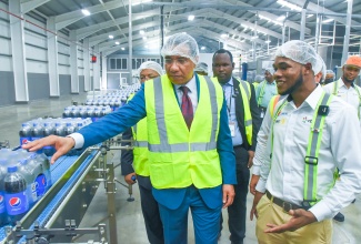 Prime Minister, the Most Hon. Andrew Holness (left), listens as Manufacturing Chief, Pepsi Cola Jamaica, Javon Salmon, explains some of the features of the conveyor belt during a tour of the company’s new US$30-million state-of-the-art production line at its Spanish Town Road facility in Kingston recently. 
