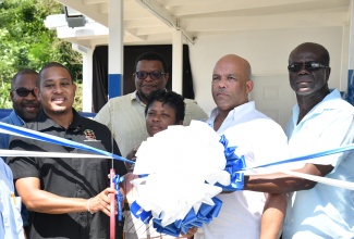 Minister of Agriculture, Fisheries and Mining, Hon. Floyd Green (left, foreground), leads a ribbon-cutting exercise symbolising the recent official handover of a communal milking parlour in Hillside, St. Thomas. Joining the Minister are (from left) Jamaica Dairy Development Board (JDDB) Chief Executive Officer, Devon Sayers, and Chairman, Dr. Derrick Deslandes; Councillor-Caretaker, Seaforth Division, St. Thomas, Sheroo Stevens; Member of Parliament, St. Thomas Western, James Robertson; and Chairman, St. Thomas Rural Agricultural Development Authority (RADA), Dean Jones.


