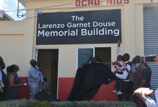 Minister of Local Government and Community Development, Hon. Desmond McKenzie (fourth left), is joined by family, friends and colleagues of late firefighter, Lorenzo Garnet Douse, for the formalities during a ceremony for the official renaming of the Ocho Rios Fire Station in St. Ann in his honour, on Thursday (November 30). The facility is now called the ‘Lorenzo Garnet Douse Memorial Building’.

