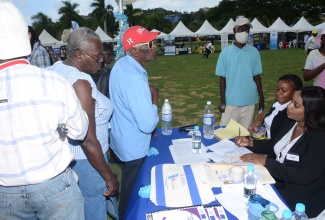 Legal Administrative Assistant and Office Manager for the Legal Aid Council’s Montego Bay Office, Nadeen James-Palmer (right, seated), and Clerical Assistant, Rochelle James (second right, seated), assist persons with legal advice during the inaugural justice fair for persons with disabilities, at the Harmony Beach Park in Montego Bay, St James, on December 7.