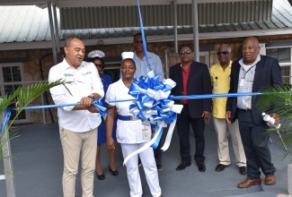 Minister of Health and Wellness, Dr. the Hon. Christopher Tufton, cuts the ribbon to open the newly refurbished waiting area at the Mandeville Regional Hospital on Thursday (December 14). Looking on (in the foreground) is Nurse Janett Bonner-Waugh. Others in the background (from left) are Matron Sadie Allen; Head of the Opthalmology Department, Dr. Gavin Henry; Chief Executive Officer (CEO) of the hospital, Alwyn Miller; Senior Medical Officer, Dr. Everton McIntosh; and Regional Director for the Southern Regional Health Authority (SRHA), Michael Bent.