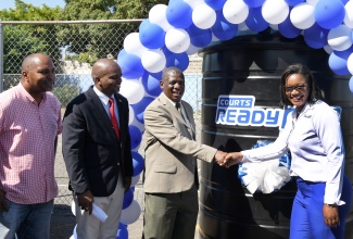 General Manager for Courts Ready Cash, Atasha Bernard (right), hands over a water tank to Principal of Gaynstead High School, Liston Aiken (second right), at the institution in Kingston on November 30. Looking on (from left) are Member of Parliament, St. Andrew South Eastern, Julian Robinson, and Senior Education Officer, Ministry of Education and Youth, Dr. Ewan Williams. The tank was provided under the company’s corporate social responsibility initiative, aimed at improving access to water in schools across the island.