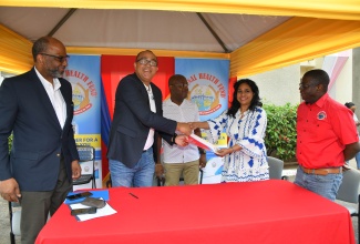  Minister of Health and Wellness, Dr. the Hon. Christopher Tufton (second left), presents a signed contract to Assistant Manager at Fleet Diagnostic Laboratory, Neesha Graham (second right), during the launch of the National Health Fund (NHF) Prostate Specific Antigen (PSA) Test facility on February 4, at the Jamaica Cancer Society (JCS), Lady Musgrave Road, St. Andrew. Looking on are (from left) Chairman of the JCS, Earl Jarrett; Acting Chairman of the NHF, Shane Dalling and Chief Executive Officer of the agency, Everton Anderson.