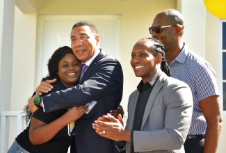 Prime Minister, the Most Hon. Andrew Holness  (second left), embraces Shaniel Francis (left), after presenting her with the keys to her new three-bedroom house under the New Social Housing Programme (NSHP) at Casabanna in Clifton, St. Catherine, on December 19 . Sharing the moment are Member of Parliament St. Catherine East Central, Hon. Alando Terrelonge (right); and Member of Parliament, St. Catherine South Eastern, Robert Miller.